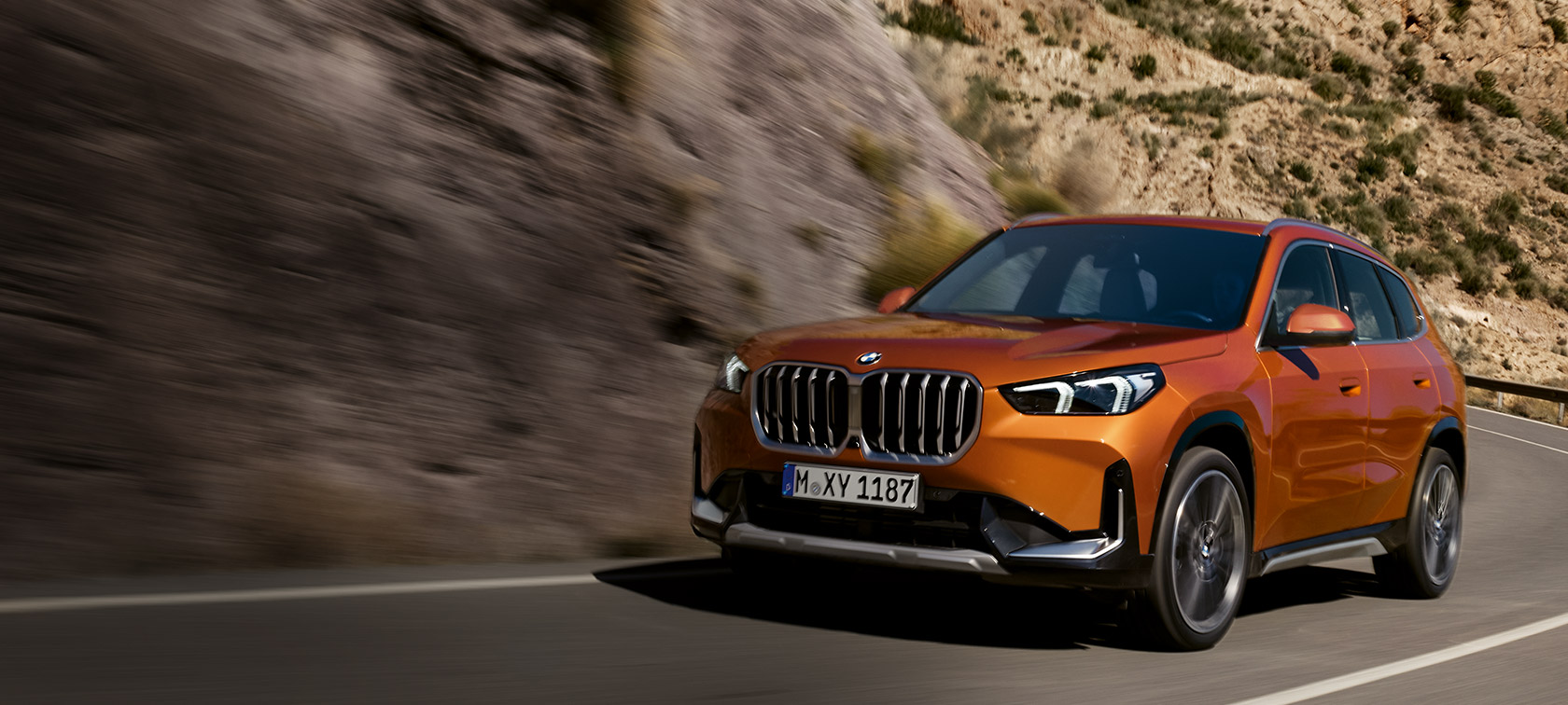 BMW X1 U11 xLine Utah orange metallic три четвърти изглед отпред в движение по път